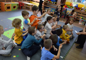 Dzieci siedzą w grupce przed tablicą, w rękach trzymają emblematy z namisem "Tak"